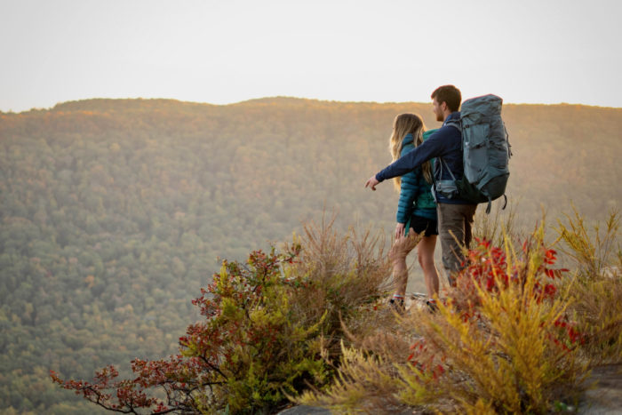 Two hikers stand at an overlook while wearing backpacking backpacks