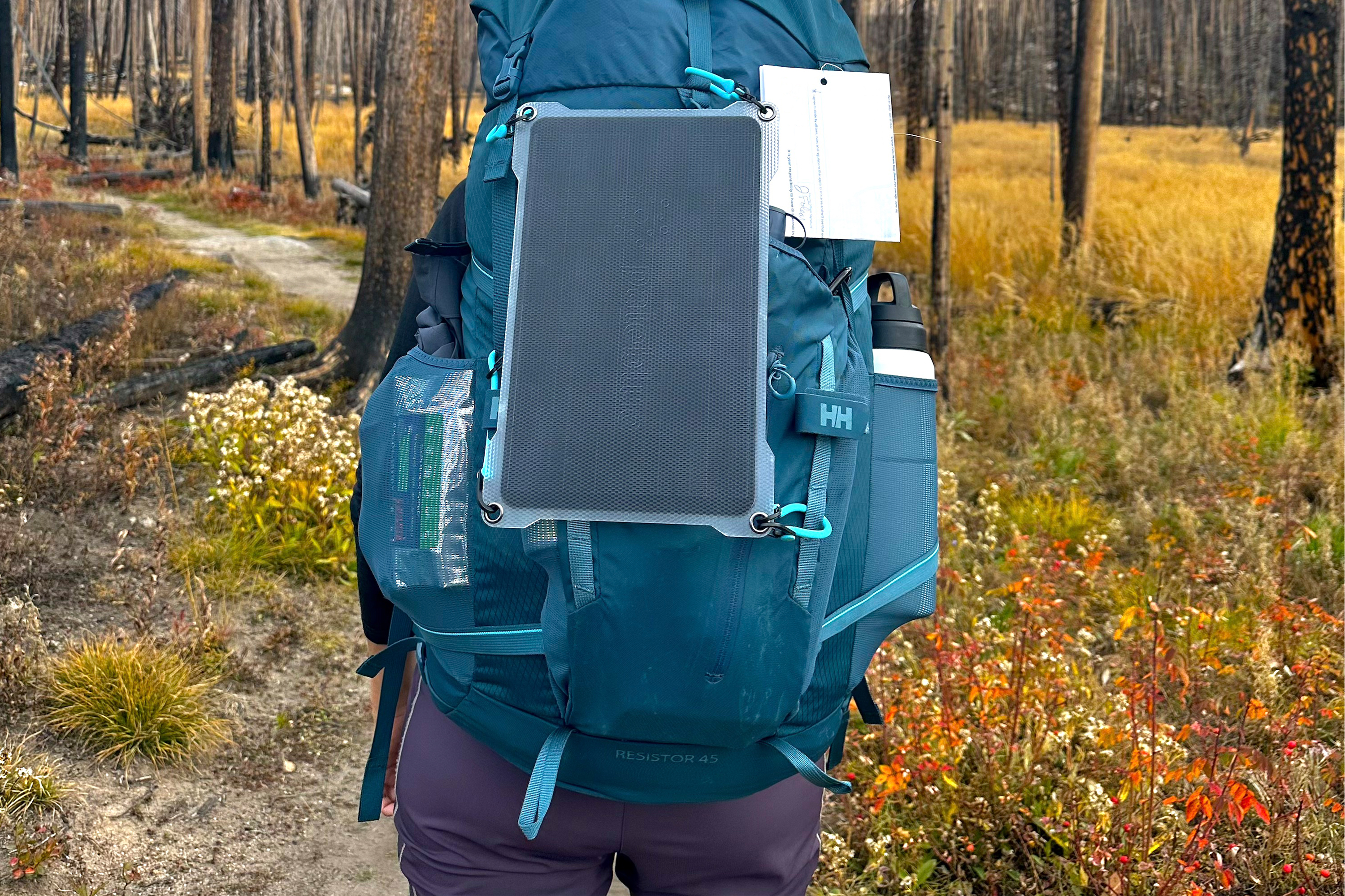 a pale blue earth brand single solar panel attached to a blue hiking backpack